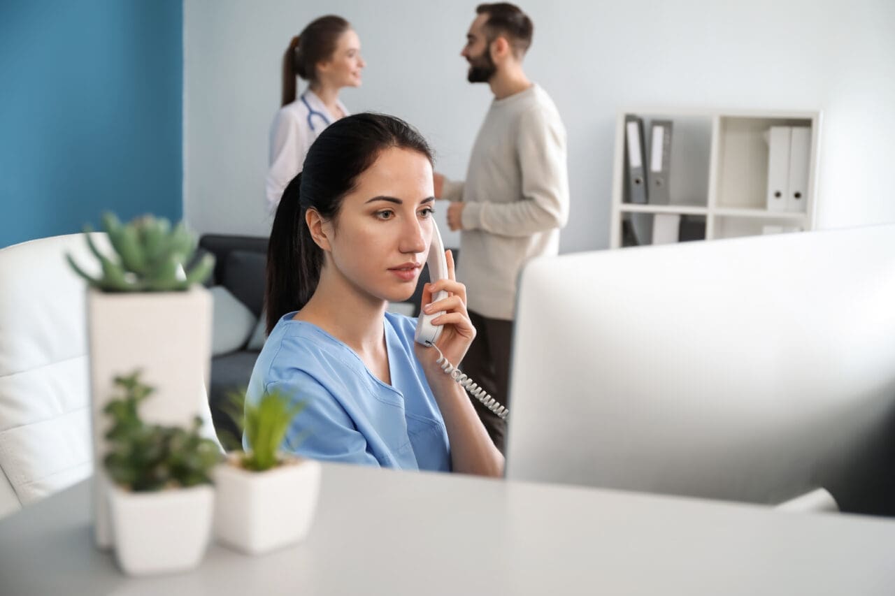 Female receptionist talking by phone in clinic