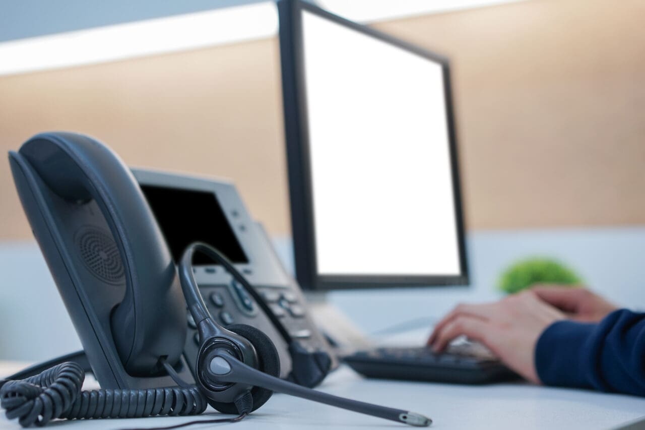 close up on headphone telephone with employee working at desktop