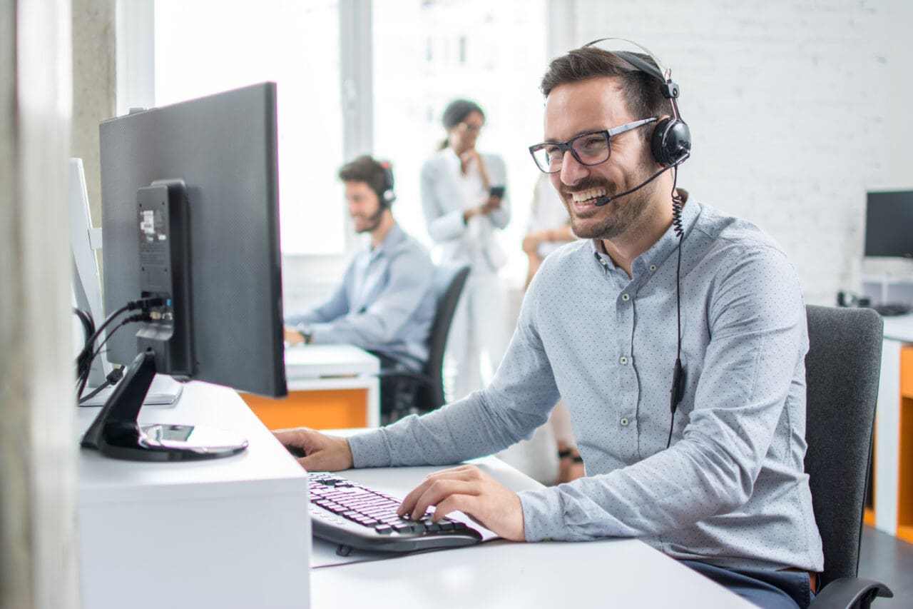 Smiling customer support operator with hands-free headset working