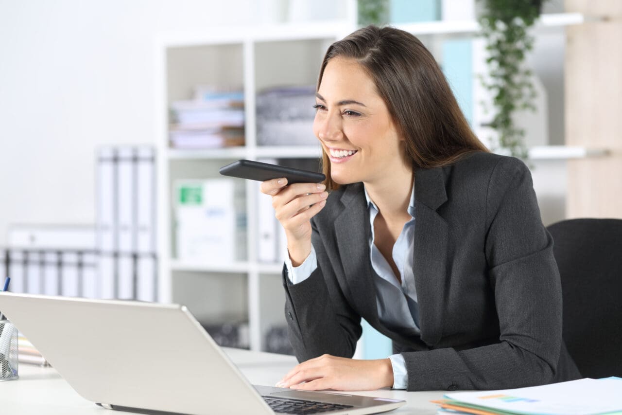 Happy executive using voice recognition on phone at office