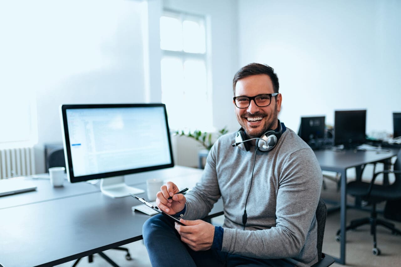 Portrait of a software developer working at modern office with a Mac computer