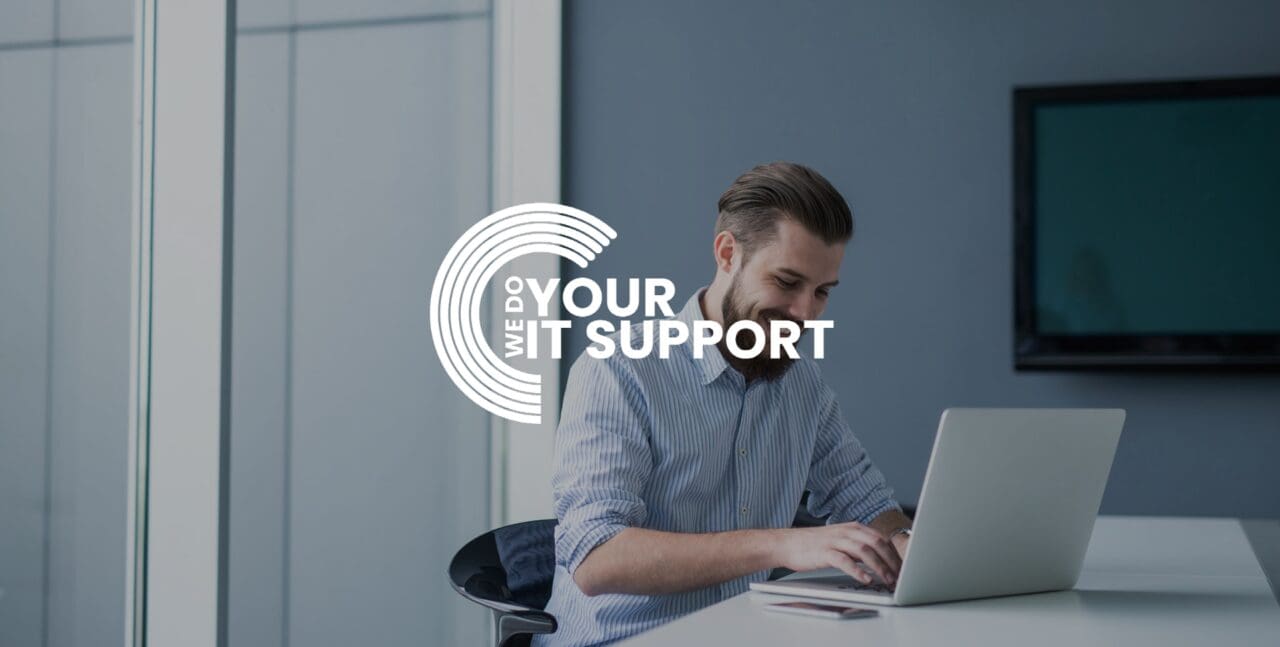 WeDoYourITSupport white logo on background of man working from home on Mac laptop, smiling