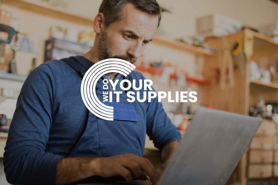 WeDoYourITSupplies white logo on background of man in workshop, typing on his laptop