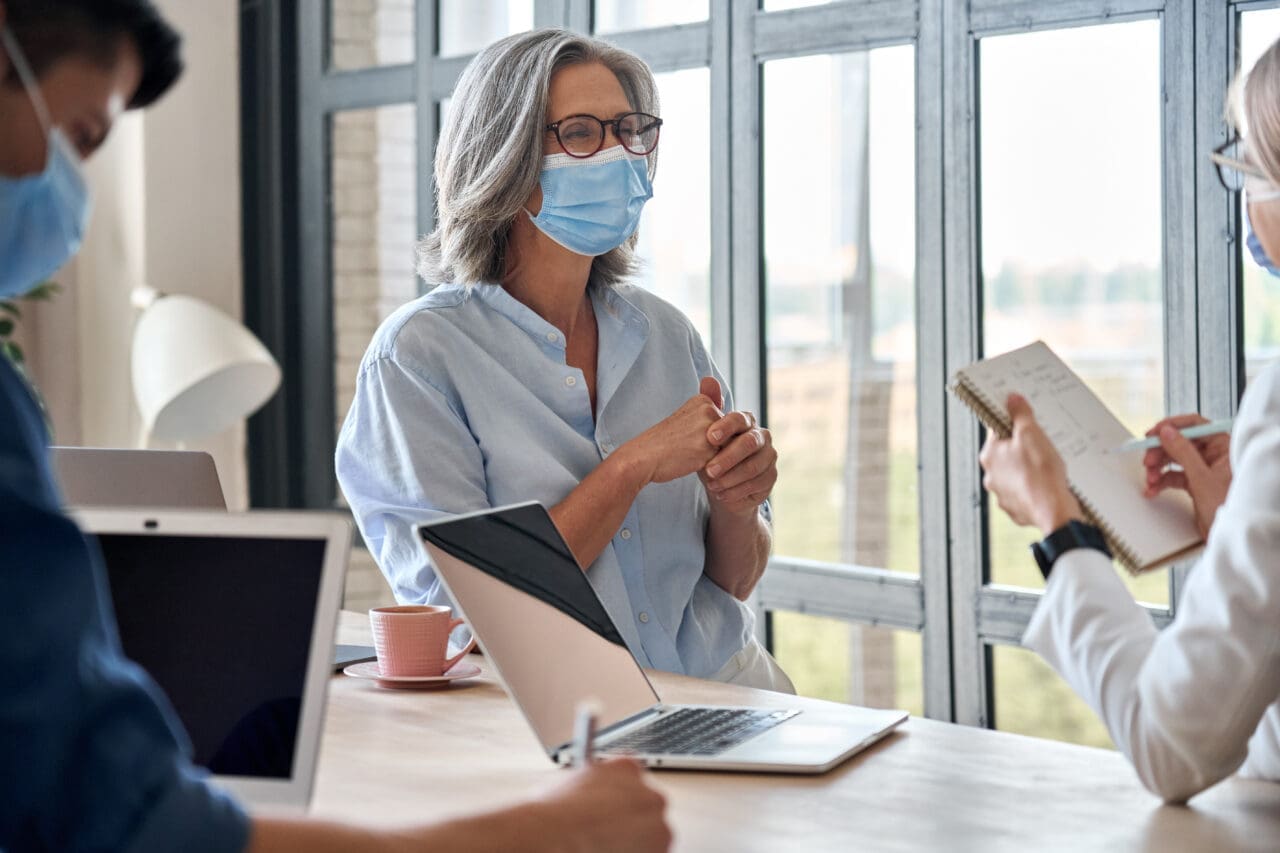 People wearing medical face masks during meeting in office.