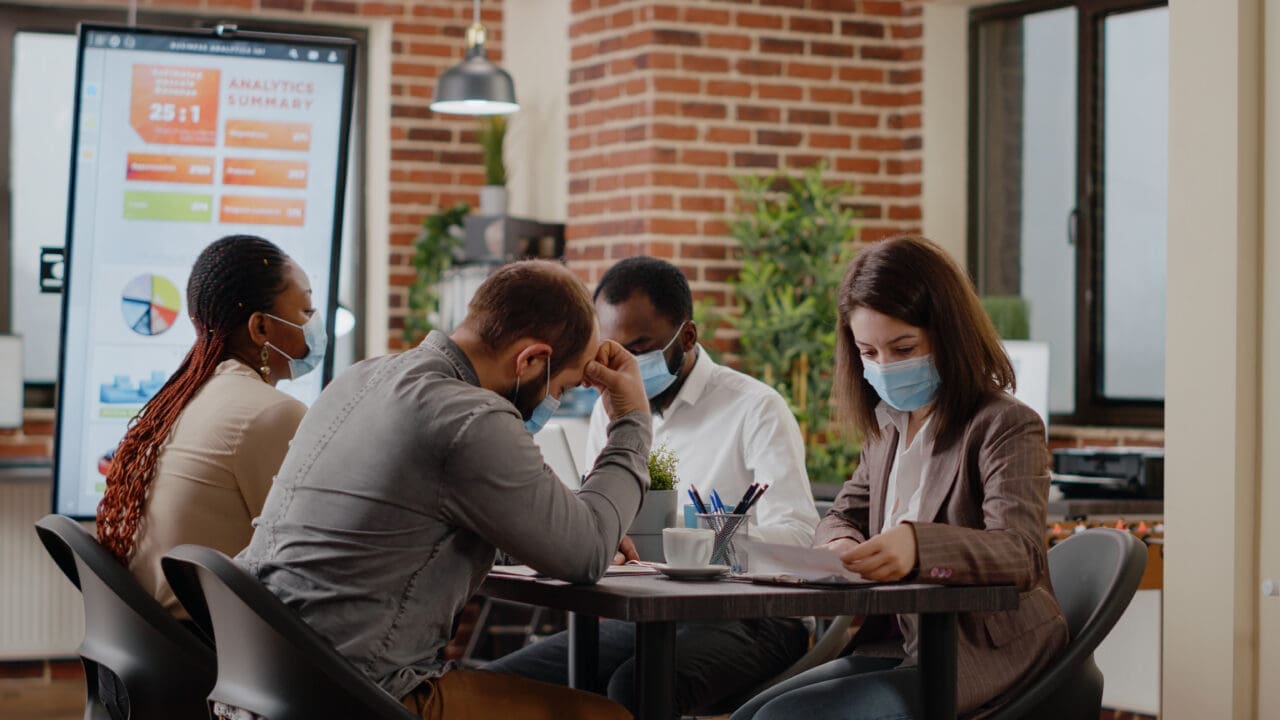 Team of diverse coworkers at business meeting in office, with face masks on