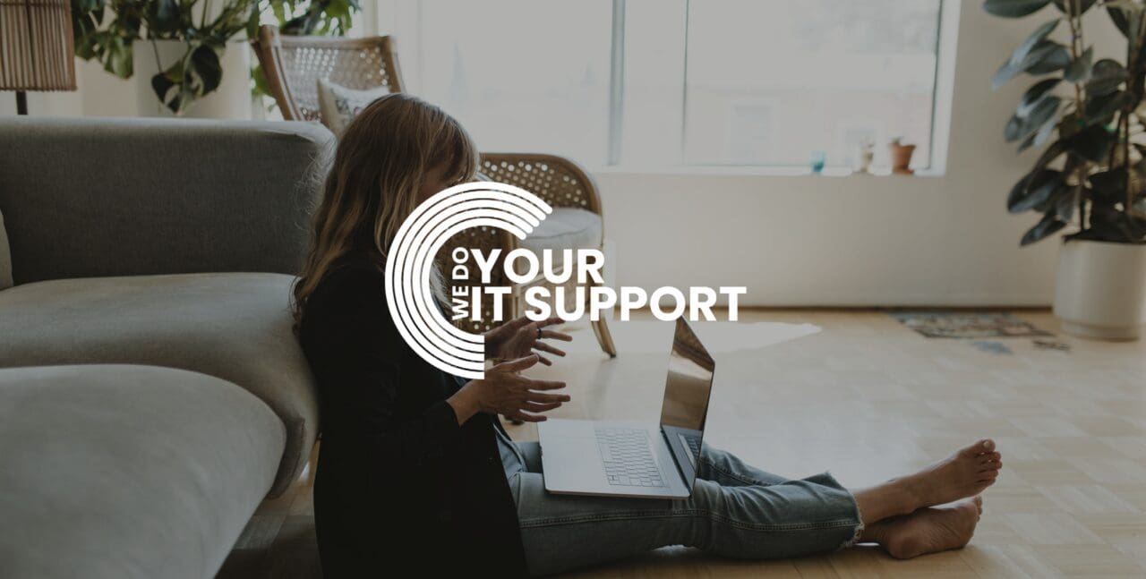 WeDoYourITSupport white logo on background of woman sat on floor at home, with Mac laptop on her lap