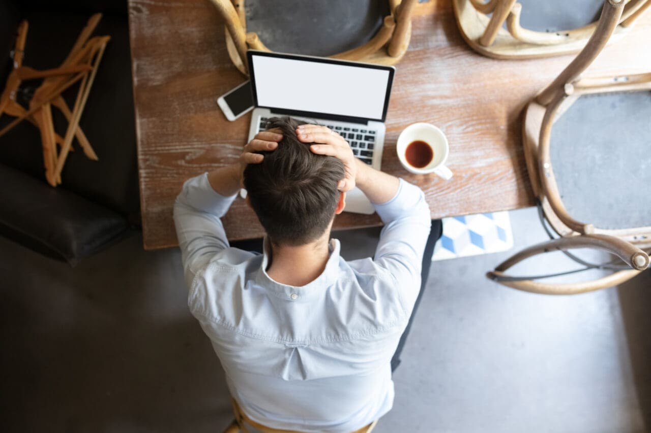 Public institutions closed due to COVID-19 or Coronavirus outbreak lockdown, stressed owner of small business alone in his cafe, looking for solution, top view