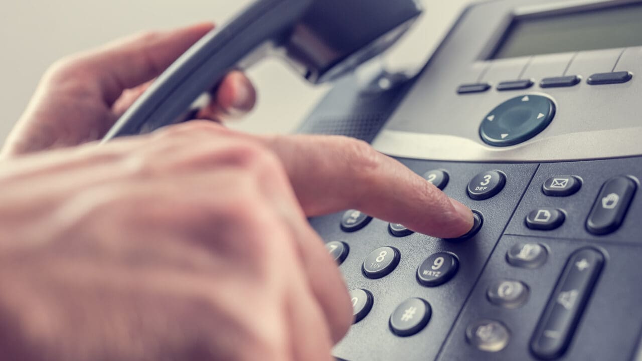 Man dialling a number on a landline telephone