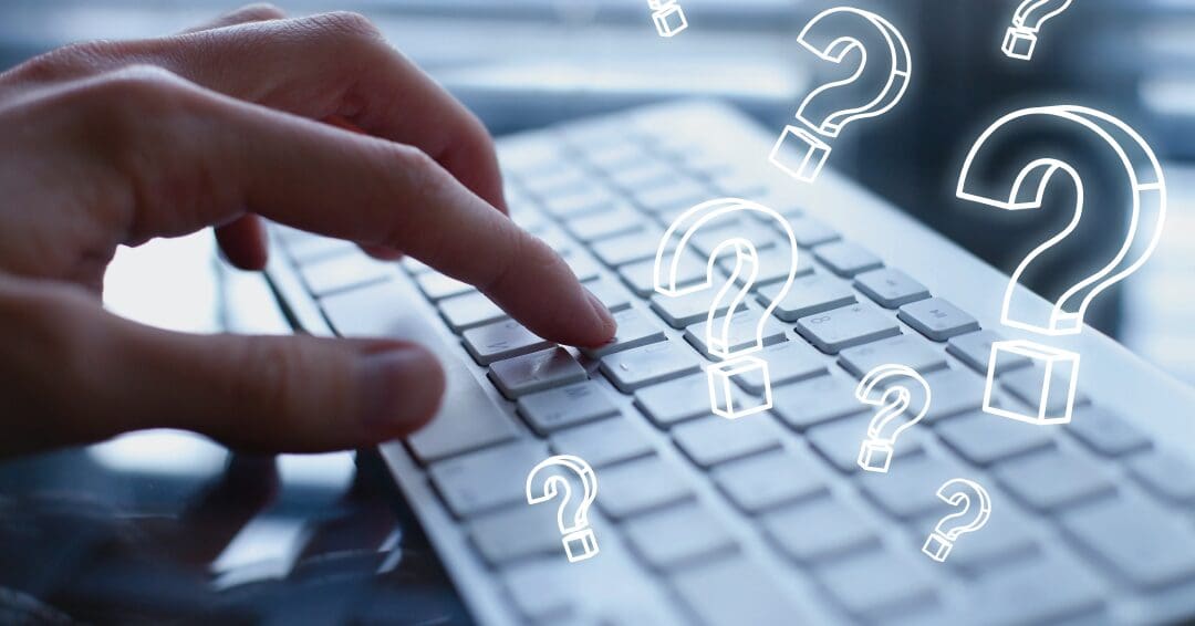 Close up on mans hand on a Mac keyboard with digital question marks surrounding it