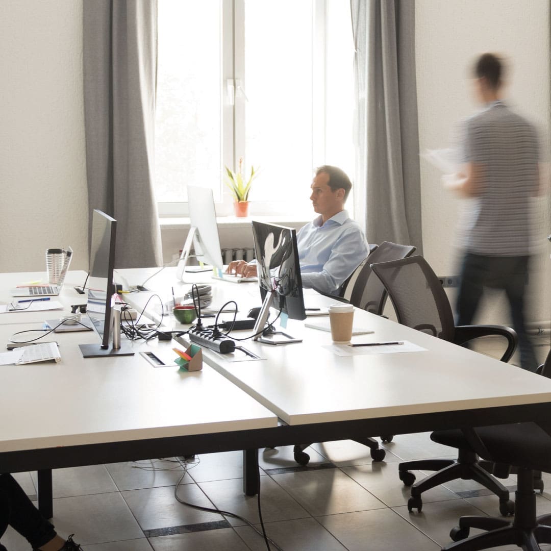 Man sat at office desk working on his Mac PC