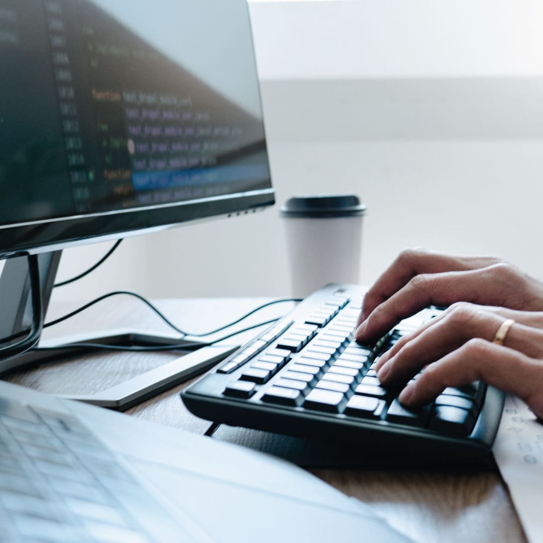 Person typing on their keyboard attached to their monitor