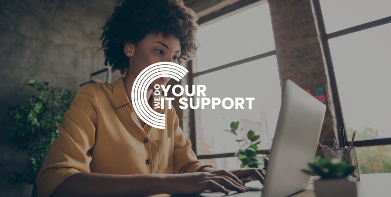 WeDoYourItSupport white logo on background of young woman sat typing on her Mac laptop