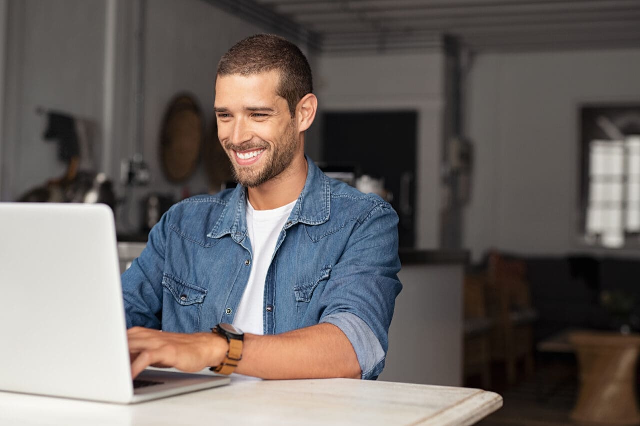 Smiling man using his Mac laptop at home