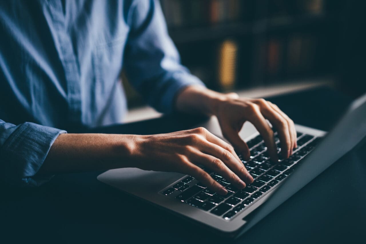 Woman working from home. Typing on her Mac laptop