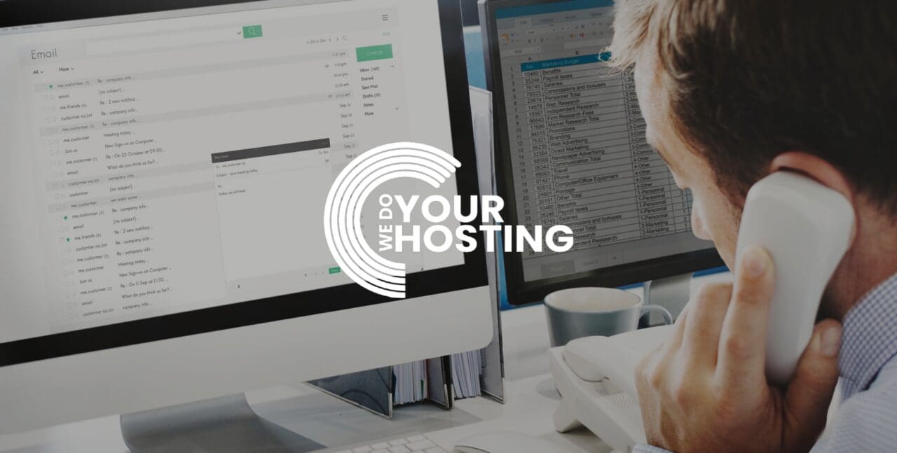 WeDoYourHosting white logo on background of man sat at work desk, with telephone to his ear, working at his Mac computer