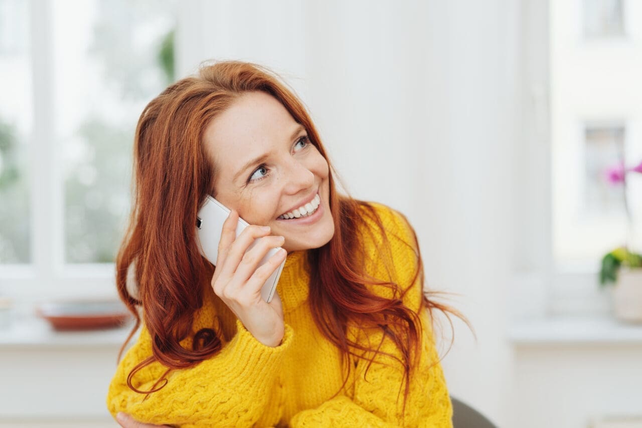 Cheerful red-haired woman talking on phone