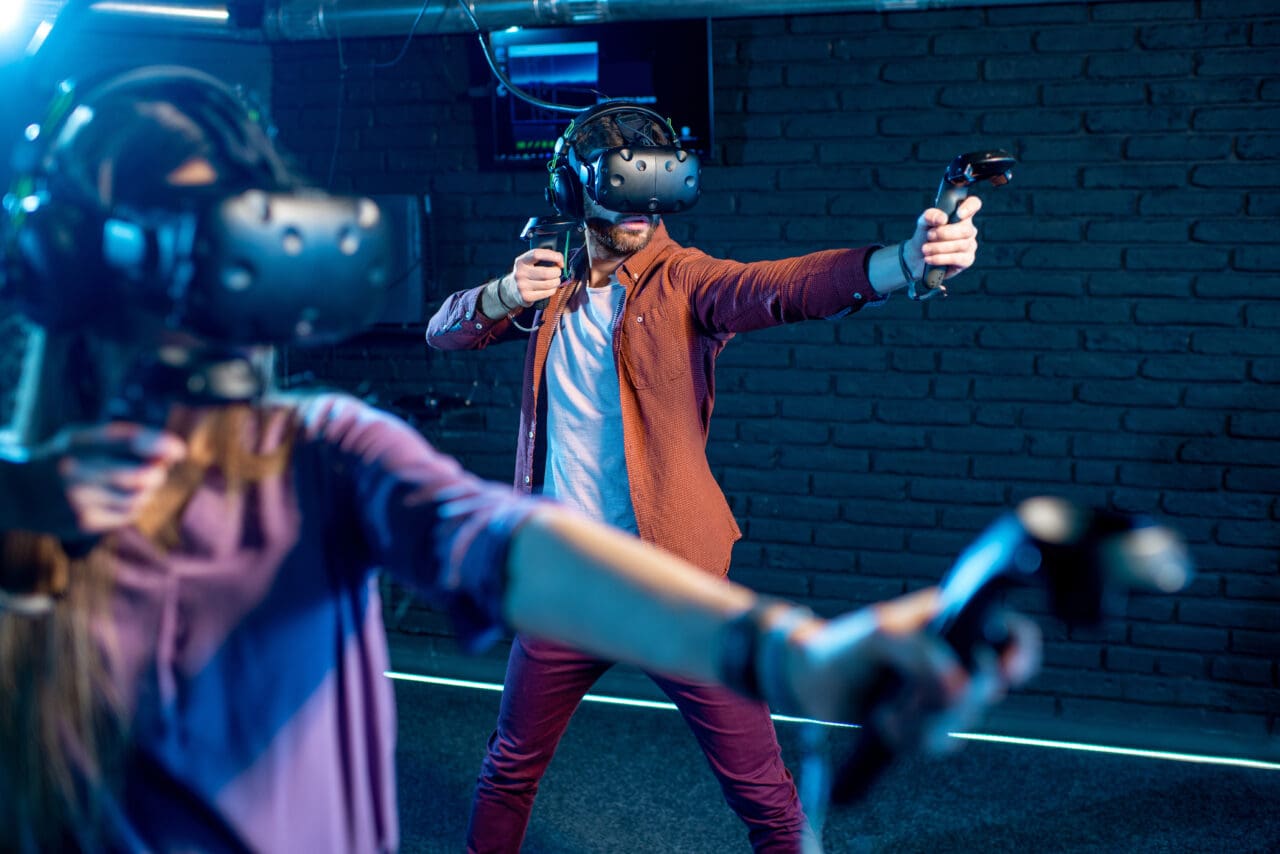 Man and woman playing game with virtual reality headset in dark room
