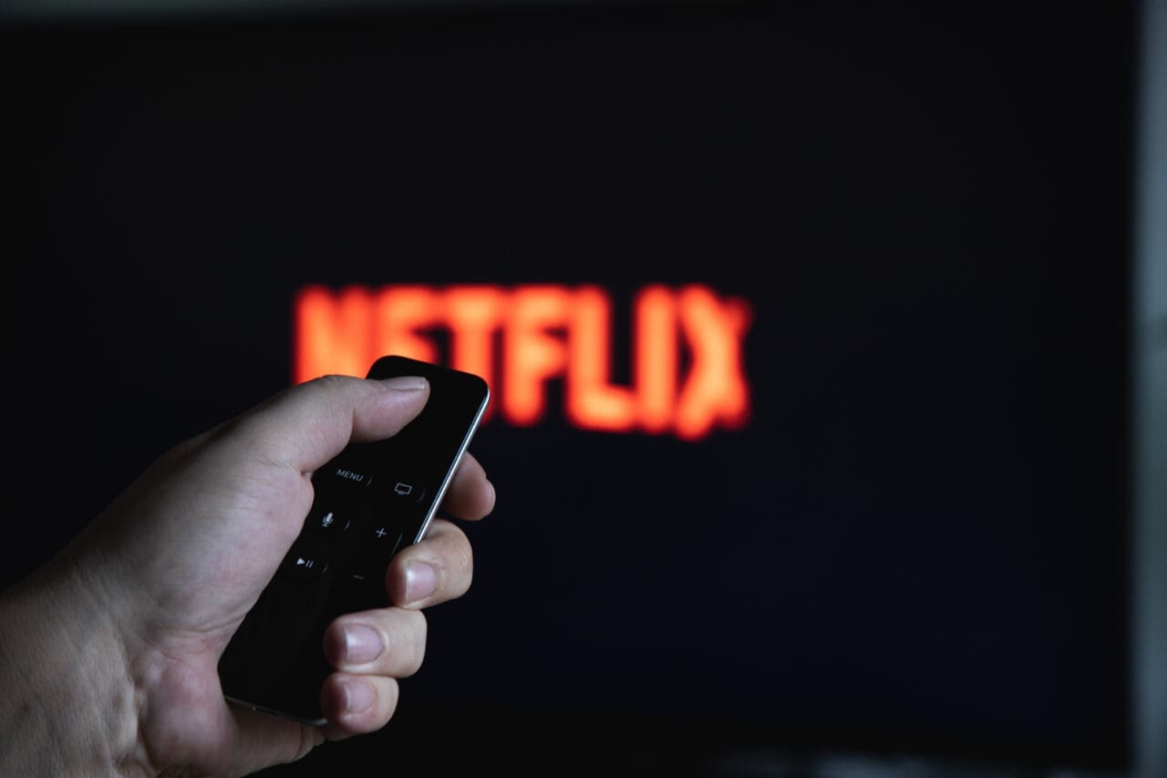 Close up of Apple TV Remote pointing at screen with netflix logo