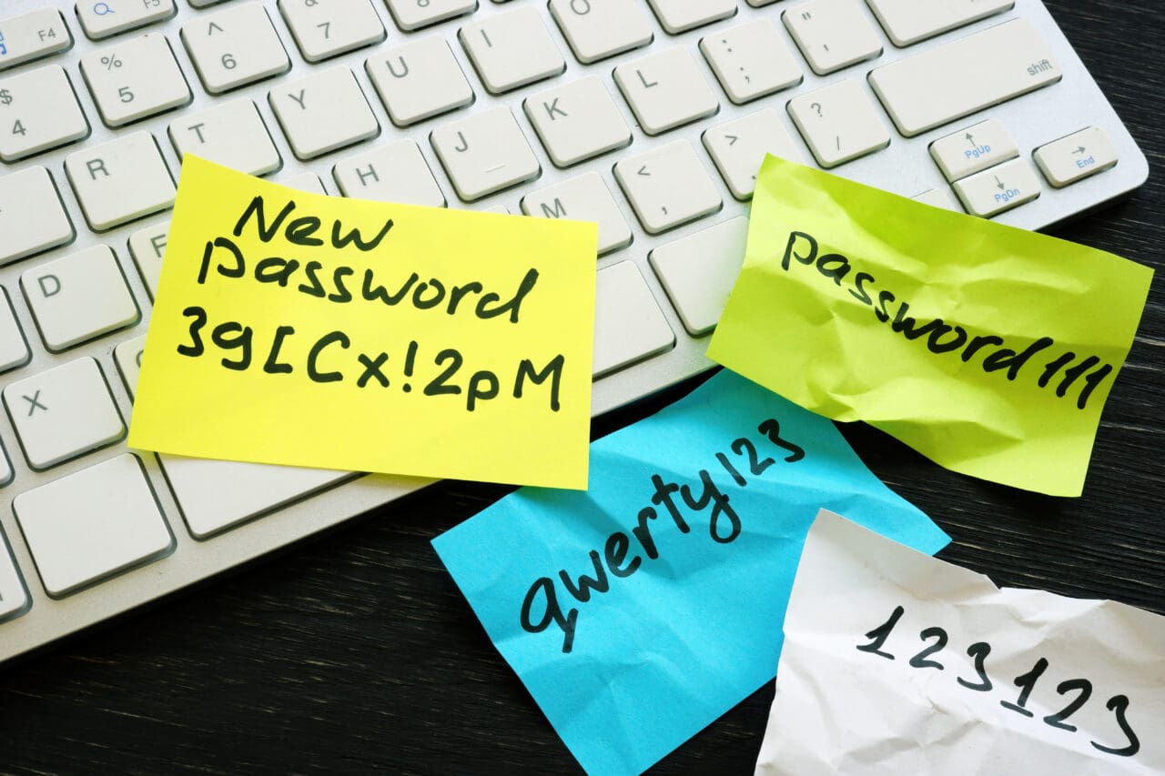 New strong password written on post it note and weak ones on post it notes near keyboard.
