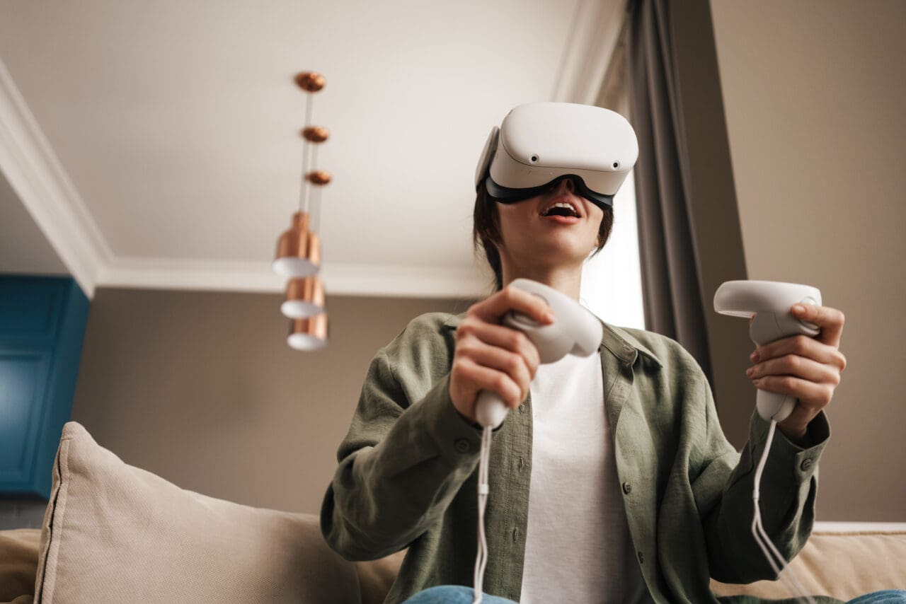 Excited woman playing online game with vr glasses and controllers