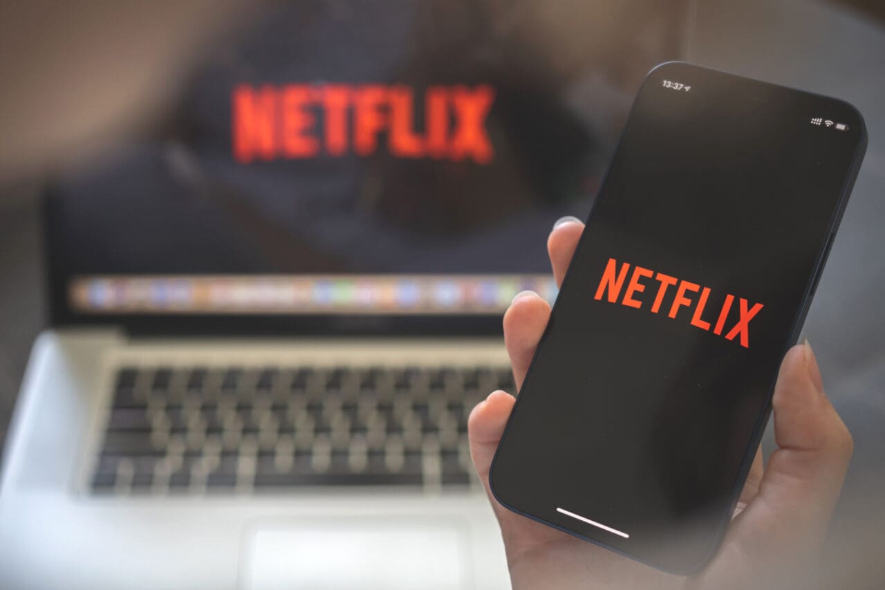 Netflix app. Woman using smartphone with streaming application. Brand logo photo