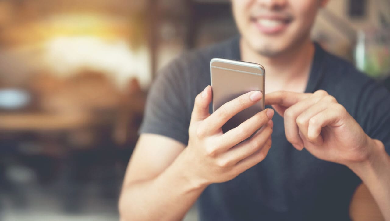 Happy male using smartphone at modern coffee shop on the phone