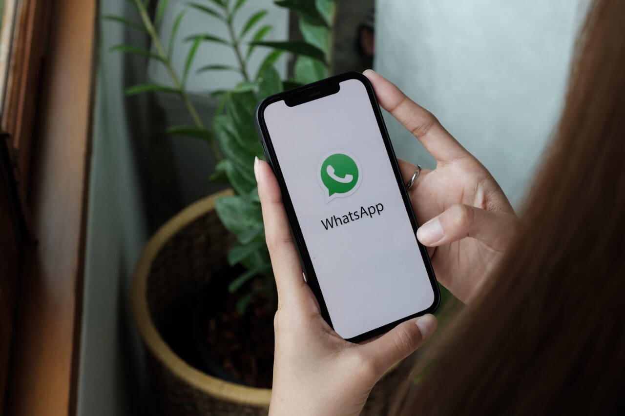 Woman holding iPhone 12 with social networking service WhatsApp on the screen. iPhone was created and developed by the Apple inc