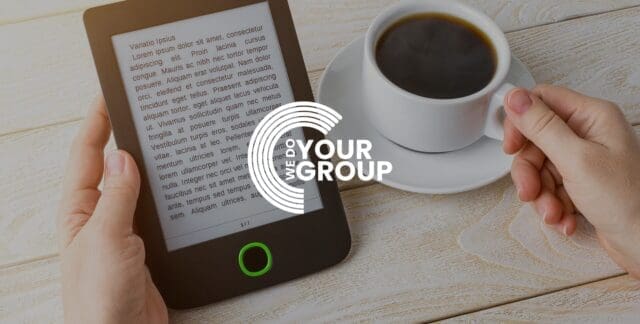 WeDoYourGroup white logo with background of Kindle and coffee mug