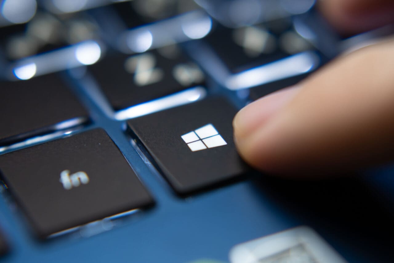 Laptop user pressing Windows icon key on keyboard