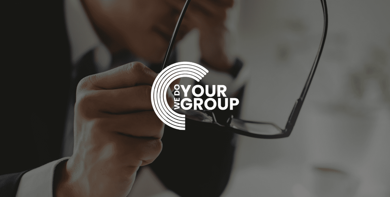 WeDoYourGroup white logo on background of man holding head in hand, taken his glasses off in other hand
