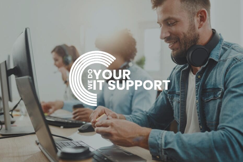 WeDoYourITSupport white logo on background of man smiling sat at his desk working