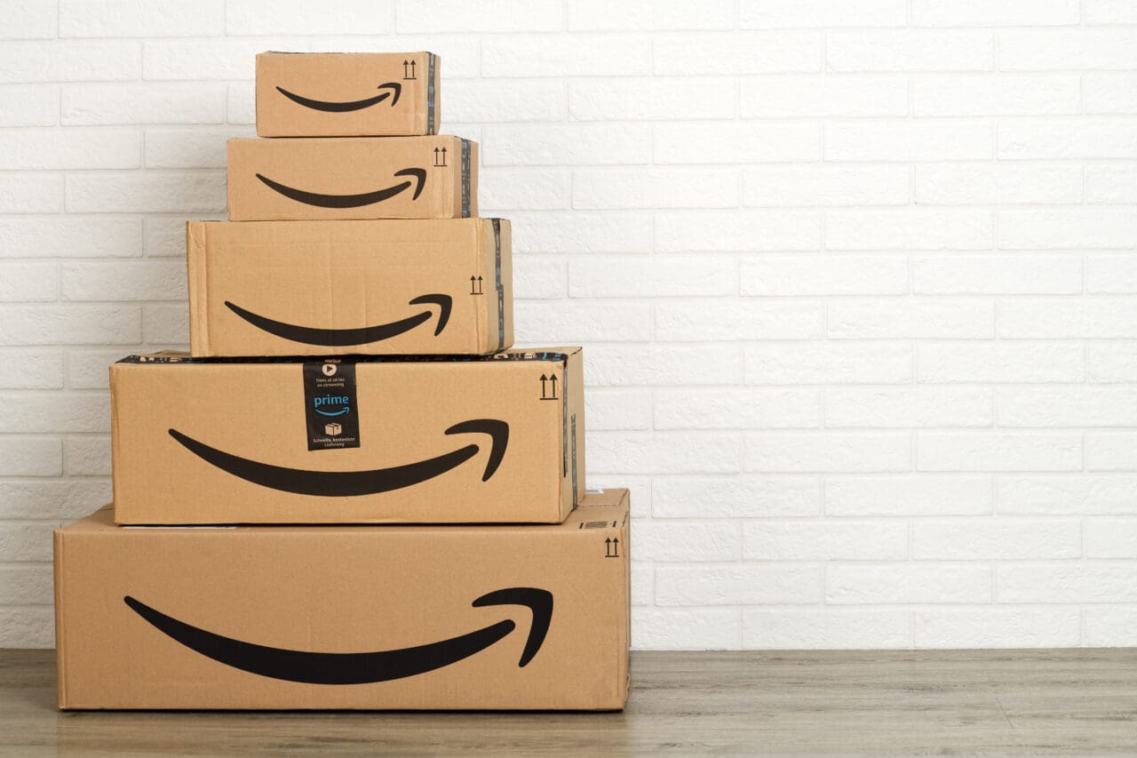 Group of Amazon cardboard boxes on white brick wall background.