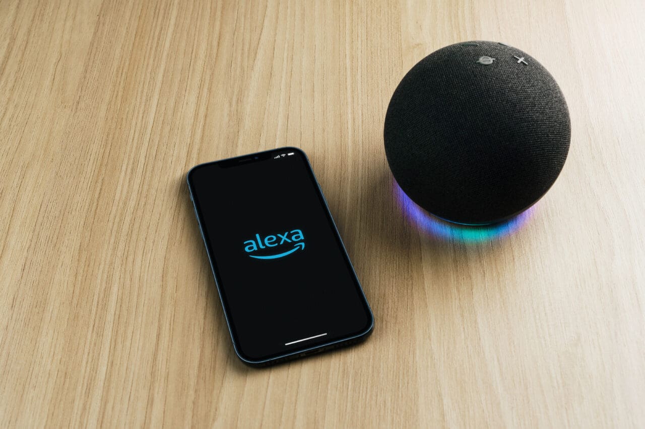 Alexa, Smart speaker and virtual assistant from Amazon company connected to smartphone app. Wooden background