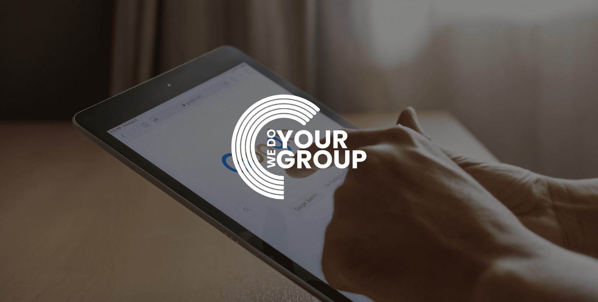 WeDoYourGroup white logo on background with person on their iPad with Google open on the screen