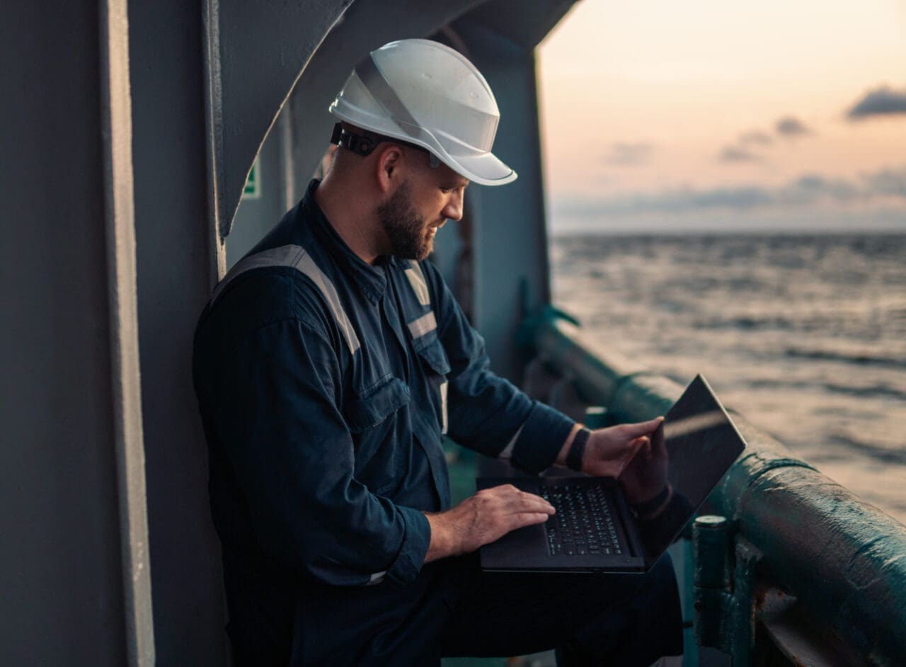 Marine chief officer or captain on deck of vessel or ship watching laptop