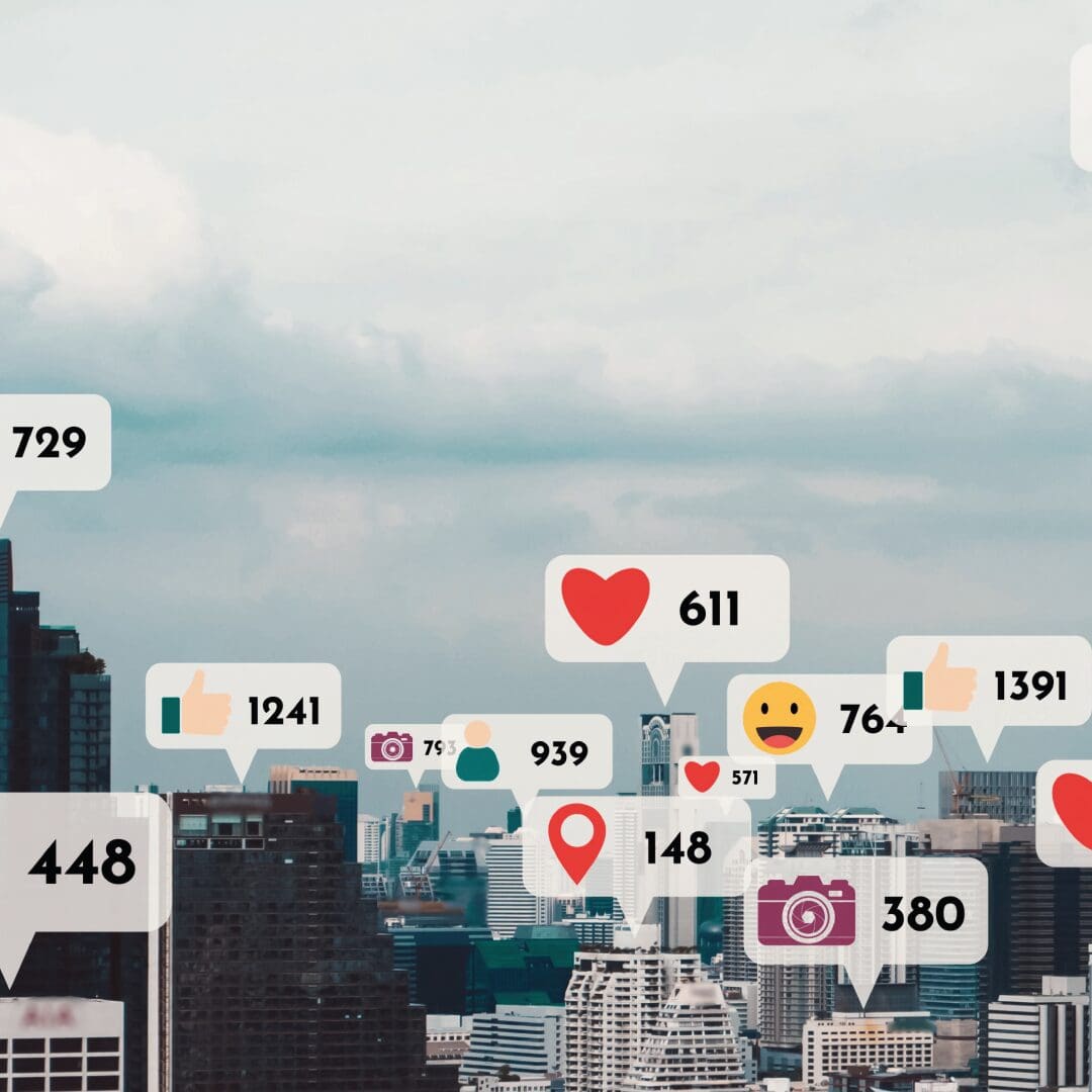 Image of city skyline with cartoon logos of social media reactions, such as heart, thumbs up, laugh emoji and camera emoji