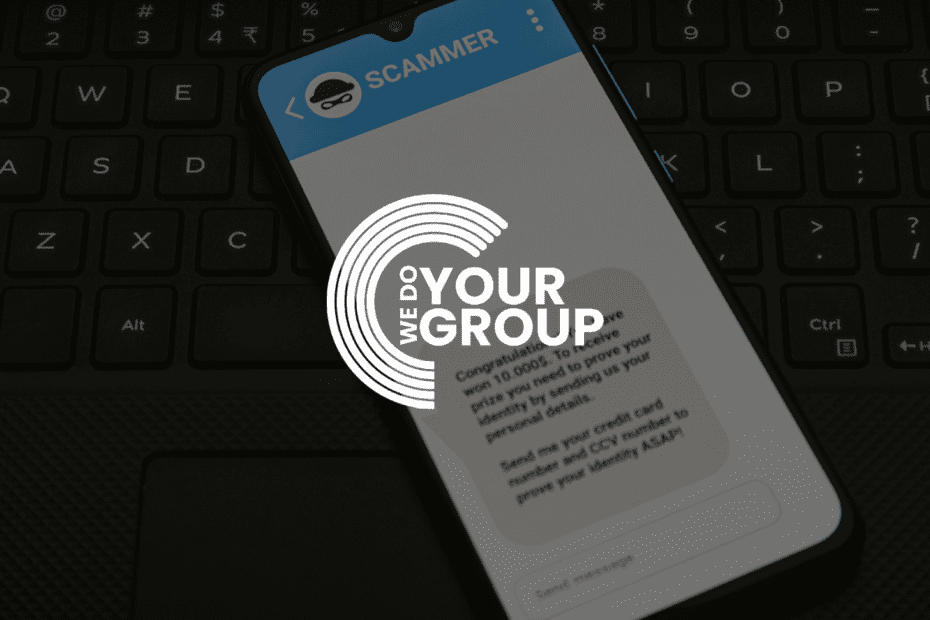 WeDoYourGroup white logo on background of mobile phone with scammer message placed on laptop keyboard.