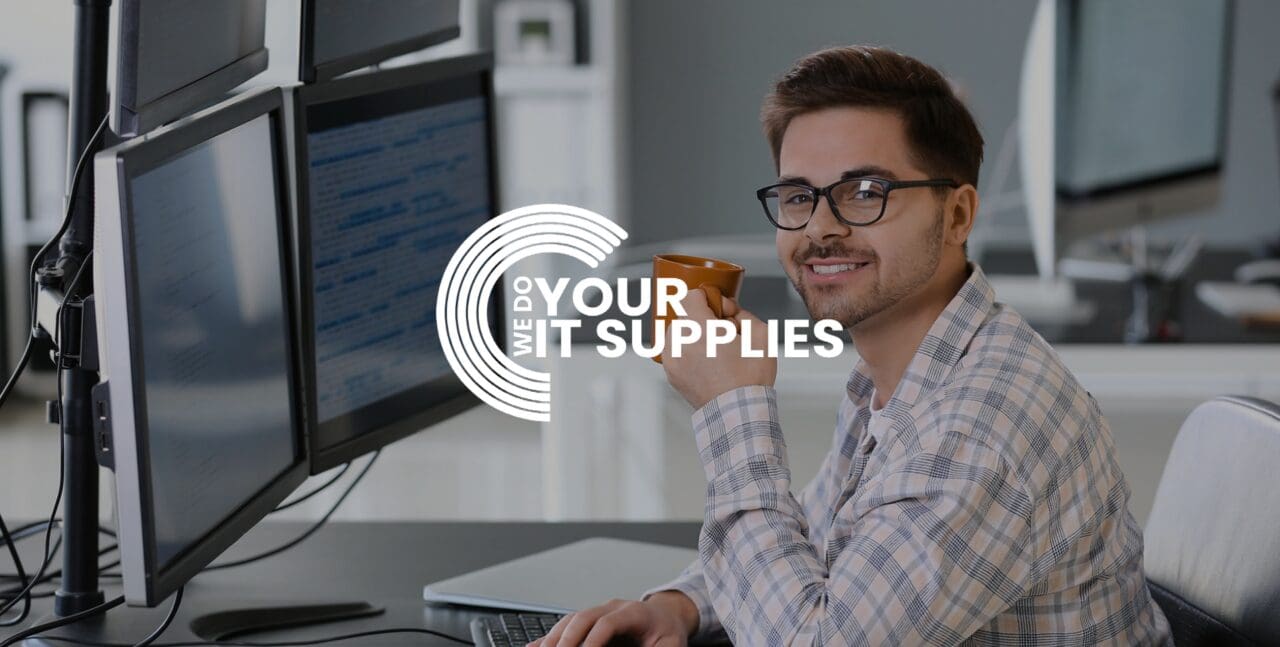 WeDoYourITSupplies white logo on background of man smiling at the camera, at his desk