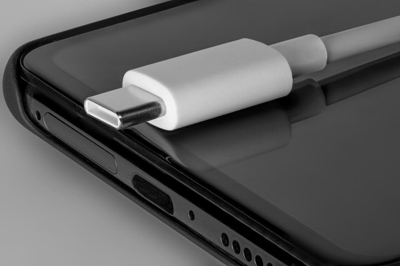USB-C white cable placed on top of a black phone. New technologies in smartphones.