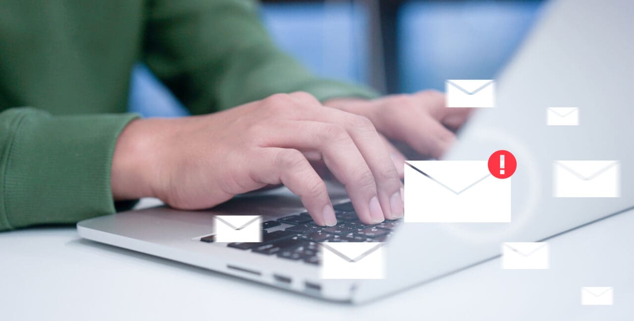 man typing on Mac laptop with white envelope icons overlaying
