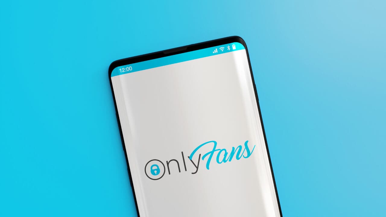 Mobile phone with OnlyFans logo on screen on light blue background