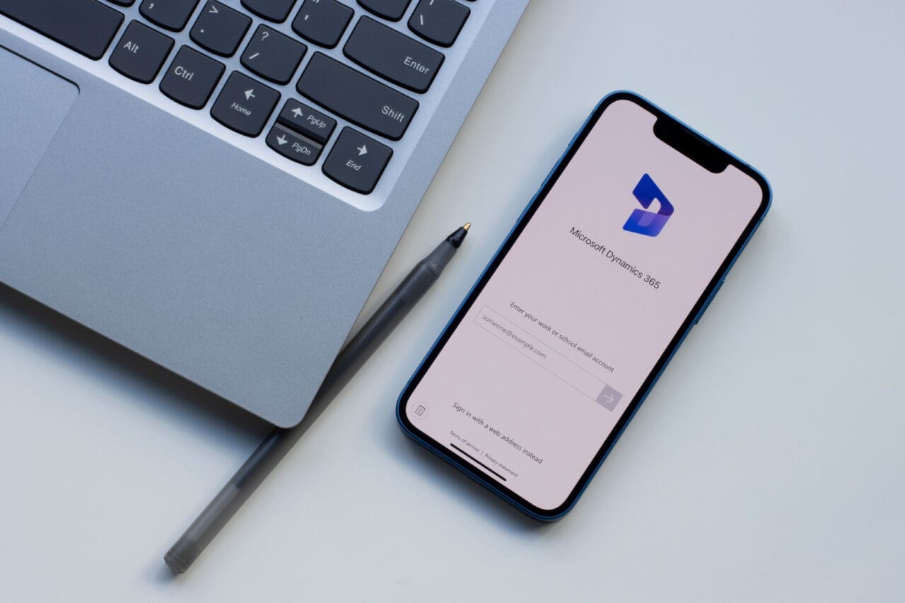 Microsoft dynamics 365 app on mobile phone, placed down next to a Mac laptop