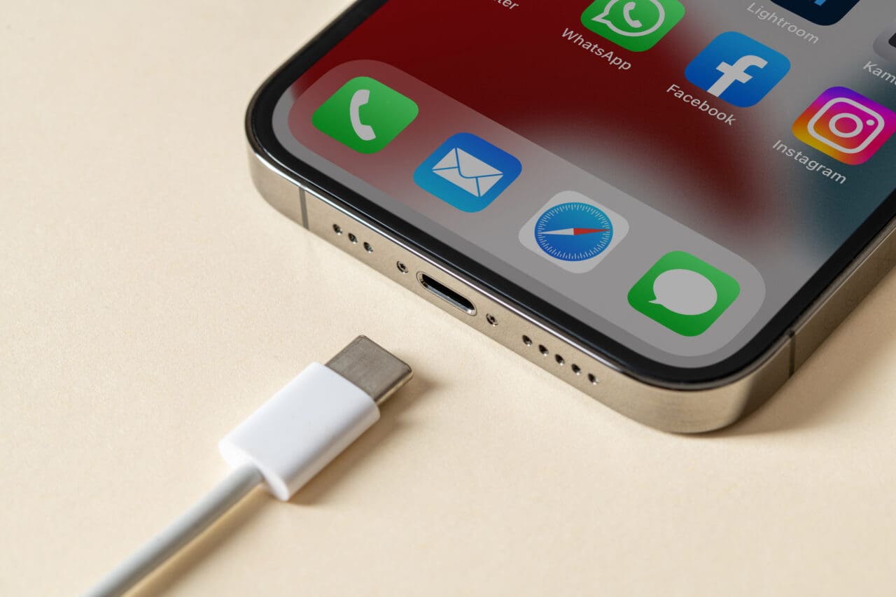 iPhone placed on desk with white USB-C charger pointing towards it