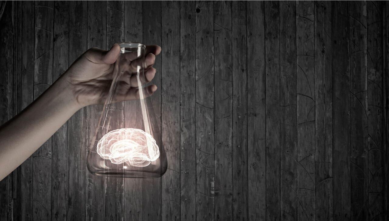 hand holding a glass flask with illuminated brain inside