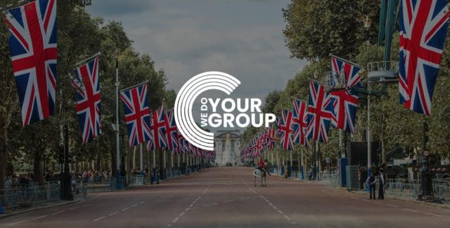 WeDoYourGroup white logo on background of Buckingham palace with United Kingdom flags placed down the road