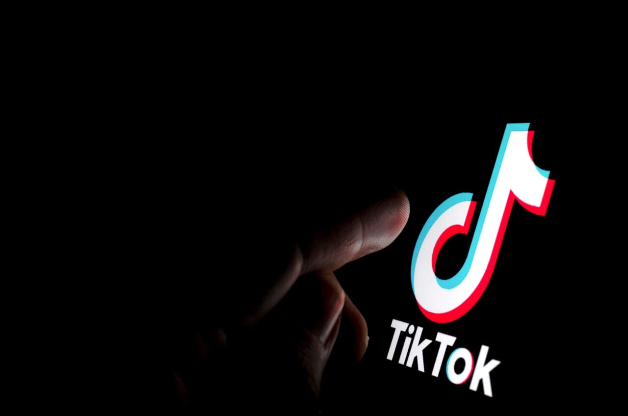TikTok app logo on the screen and a finger about to touch it.