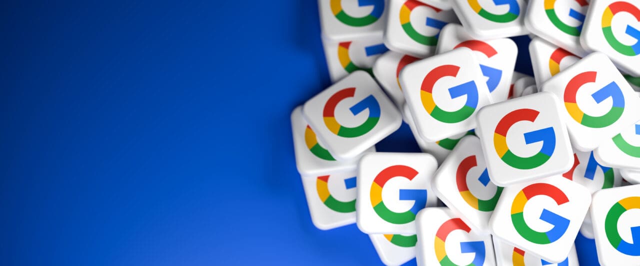 Logos of the company Google / Alphabet on a heap on a table.