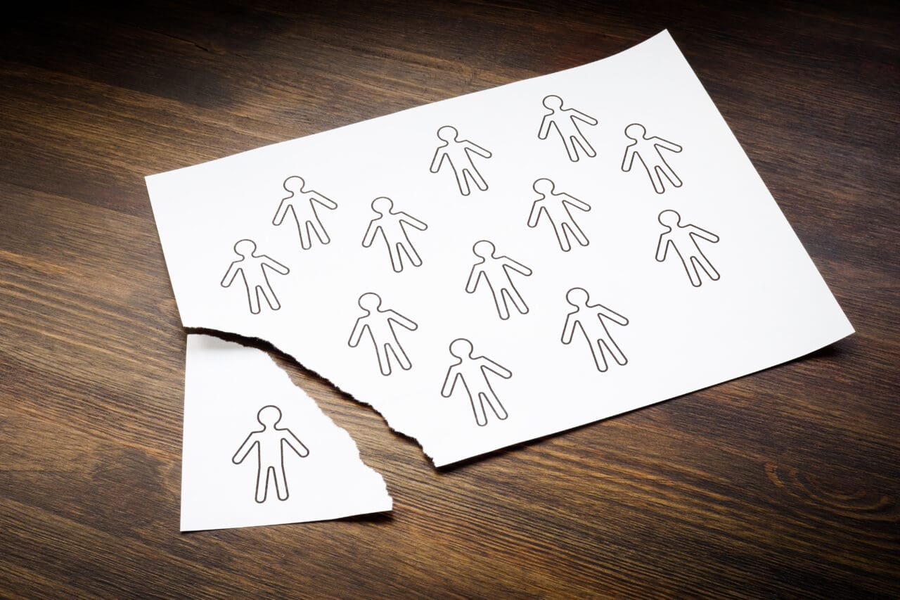 Disengaged Employees concept. Figures of people on a sheet of paper and one is torn off.