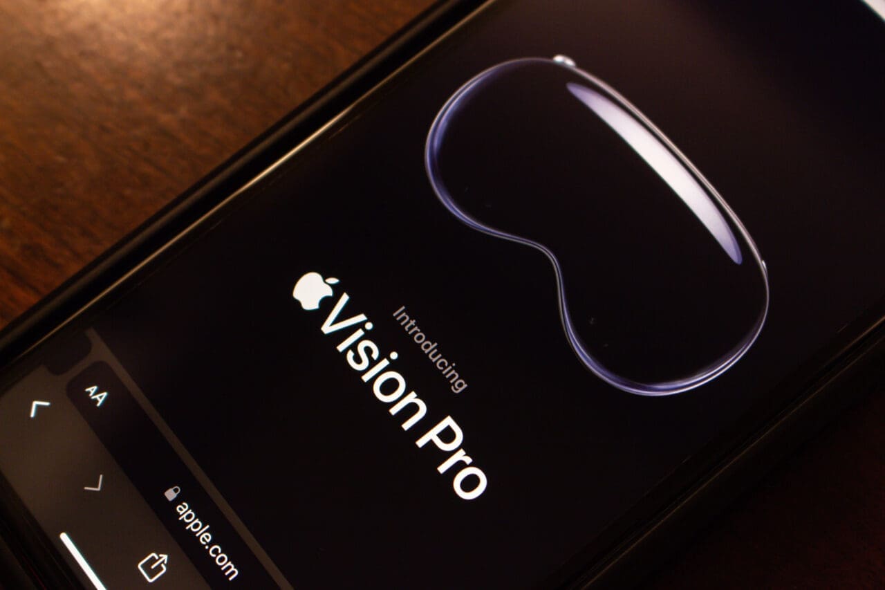An official website of Apple Vision Pro seen in an iPhone on a wooden table. Vision Pro is a mixed reality headset developed by Apple Inc.