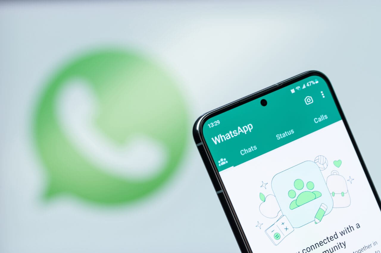 Selecting chat in whatsapp app on smartphone display close up with blurred logo background